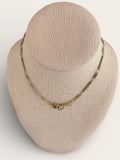 Gold necklace on a beige bust against a white background
